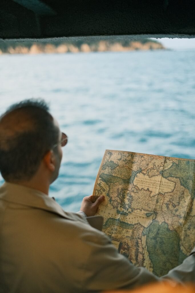 Adult man examines a historic map while traveling by sea on a boat.